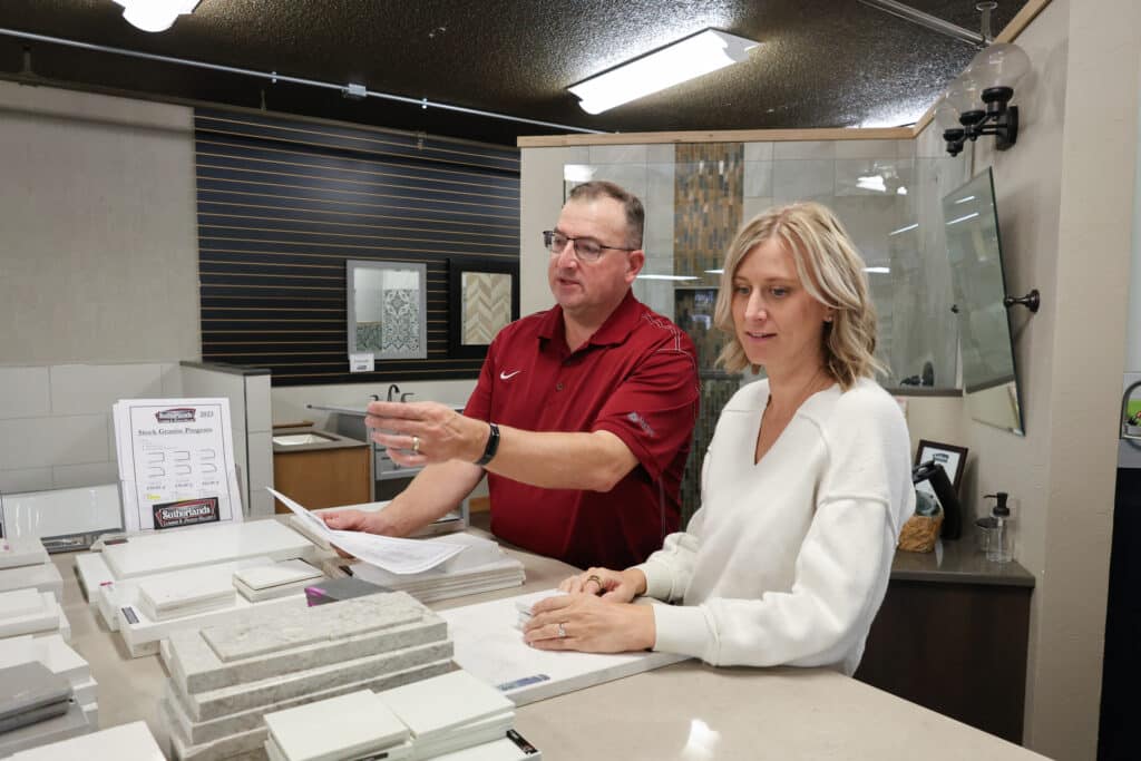 A man in a red shirt pointing out options to a woman in a white sweater.