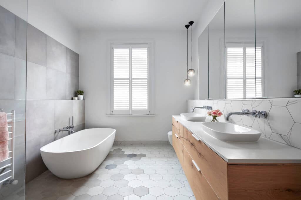 White bathroom with tile floor and large standing bathtub.